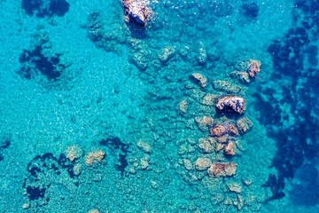 Fototapeta na wymiar Aerial view of turquoise sea water and rocks by the seashore.