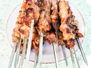 many hot cooked skewered shish kebabs on plate