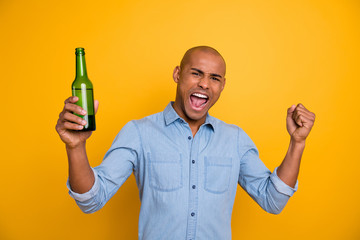 Photo of dark skin macho raise fist beer bottle yelling loud goal sport bar wear jeans denim shirt isolated bright yellow background - Powered by Adobe