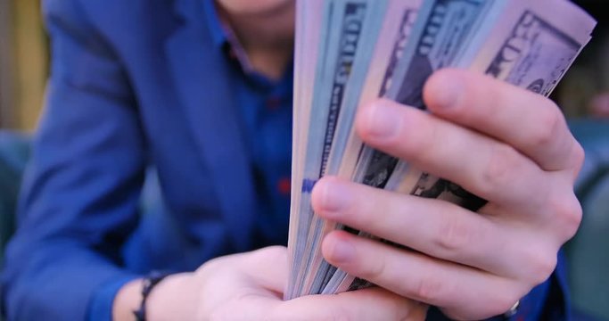 Young guy businessman freelancer counts money. Close-up hands counting a stack of money. Dollars, income, finance, business, suit