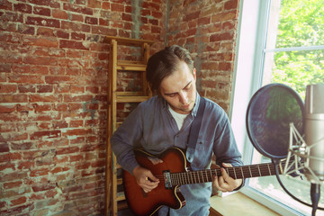 Young man recording music video blog, home lesson or song, playing guitar or making broadcast...