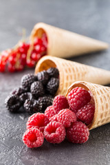 Ice cream cones with berries on a stone background