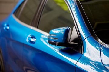 Rear-view mirror of blue car closed for safety at car parking lot,  Side mirror of gray car. Selective focus