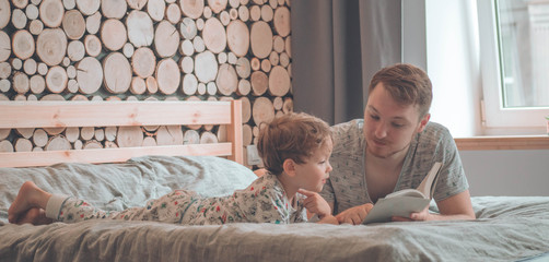 Dad and Son read a book together, smiling and hugging. Family holiday and togetherness. Happy father's day!