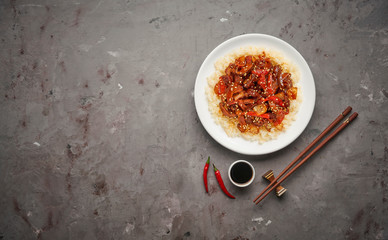 Sweet and Sour fried pork chunks with vegetables and rice on grey stone background. Top view with copy space