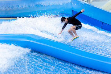 Unidentified man playing surfboard indoor extreme sport.