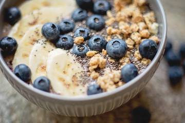 Healthy breakfast berry smoothie bowl topped with banana, granola, Blueberries and chia seeds with copy space