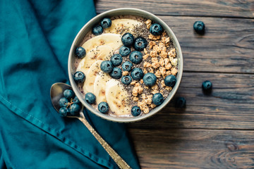 Healthy breakfast berry smoothie bowl topped with banana, granola, Blueberries and chia seeds with copy space
