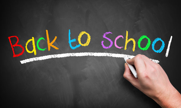 hand is writing "back to school" on chalkboard