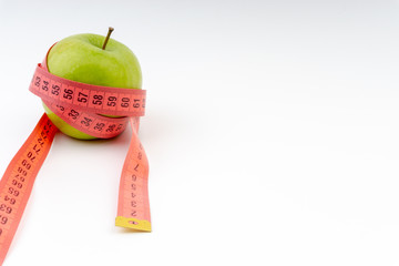 Green apple with red measuring tape. Selective focus