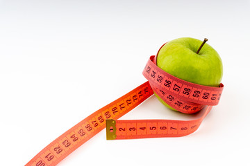 Green apple with red measuring tape. Selective focus