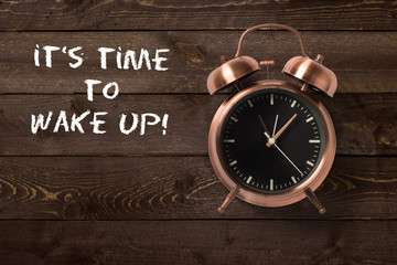 alarm clock with motivational message on wooden background