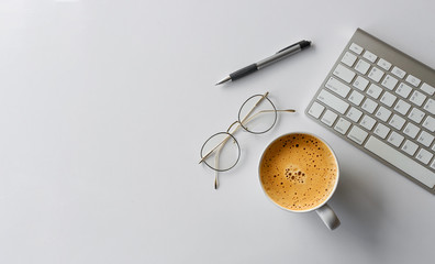 business concept. top view of office desk workspace with keyboard, pen, glasses and hot coffee cup on white table background. over light