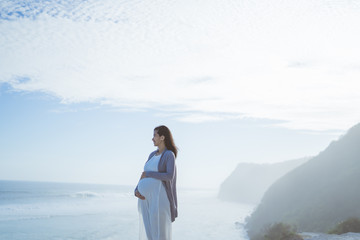 beautiful pregnant woman standing on the beach when sunrise in the morning