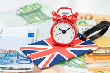 Alarm clock on Union jack, United Kingdom national flag luggage label on Euro banknotes using as countdown on Brexit England withdrawal from Euro zone, or Europe travel