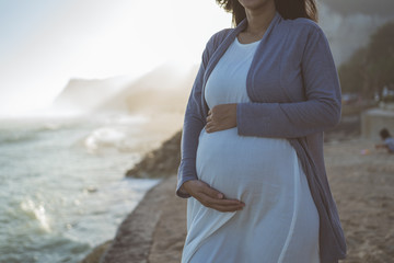 beautiful pregnant woman standing on the beach when sunrise in the morning