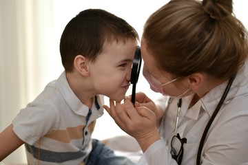 The child and the doctor are joking, gazing at each other through a magnifying glass and touching...