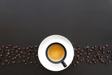 hot espresso and coffee bean on black table with soft-focus and over light in the background. top view