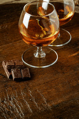 Two glasses of bourbon or scotch, or brandy and pieces of dark chocolate