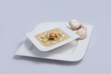 Contrasted Hero Shot of a Mushroom Soup with bread crumbs, oregano on a minimal white background with a 60 degree front facing angle