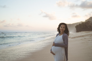 beautiful pregnant woman standing on the beach when sunrise in the morning - Powered by Adobe