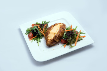 A low contrast image of a breakfast platter with cheese-filled croissant with vegetables- carrot, tomato, lettuce on a minimal white background with a 30 degree angle from front zoomed in perspective