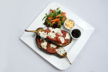 A low contrast warm Hero shot of a main course platter with grilled aubergine with buffalo cheese on a minimal white background with a 45 degree angle from a 45 degree angle from diagonal perspective.