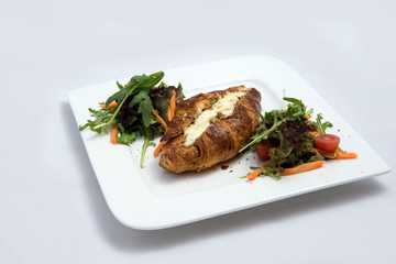 A low contrast Hero shot of a breakfast platter with cheese and zaatar filled croissant with vegetables with a 30 degree angle from front perspective