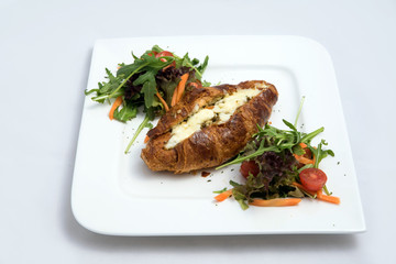 A low contrast Hero shot of a breakfast platter with cheese and zaatar filled croissant with vegetables with with a 30 degree angle from front perspective