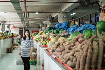 pregnant asian young woman standing carrying plastic bag when shopping at the market
