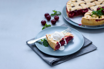 Slice of homemade cherry lattice cake on gray wooden background. Traditional american food.