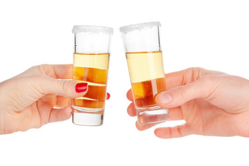 Two hands clinking shots of alcoholic beverage together