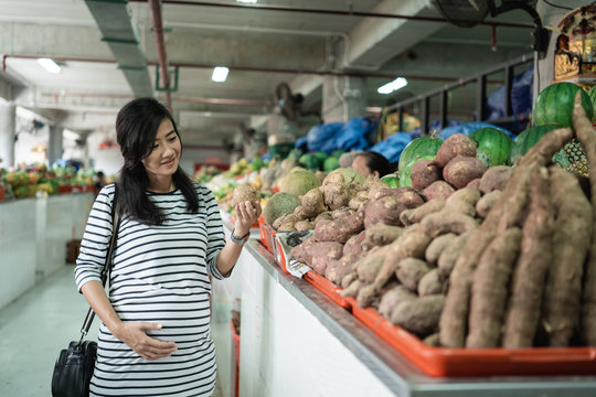 pregnant asian young woman hold items to be purchased when shopping at the market