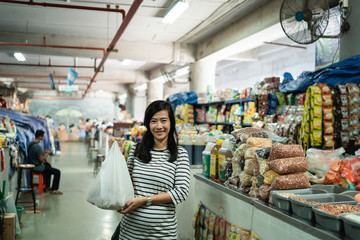 pregnant asian young woman standing carrying plastic bag when shopping at the market