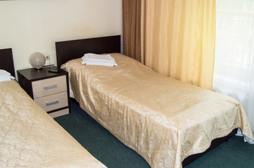Modern double room with two single beds, bedside table, towels and table lamp, cozy inexpensive...