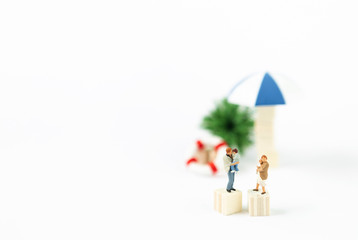 Miniature parents carrying baby over blurred beach object background, family holiday and vacation concept, happy family time
