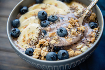Healthy breakfast berry smoothie bowl topped with banana, granola, Blueberries and chia seeds with copy space