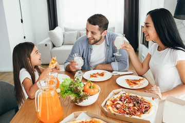 happy multi ethnic family, mother, father and daughter during dinner.Eating delicious pizza with...
