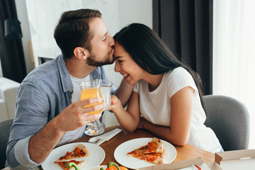 Happy couple kissing and have dinner with pizza at home. Its a good time spending home