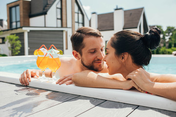 man and a woman look lovingly at each other while in the pool. Goodbye work, hi summer vacation-swimming and tanning
