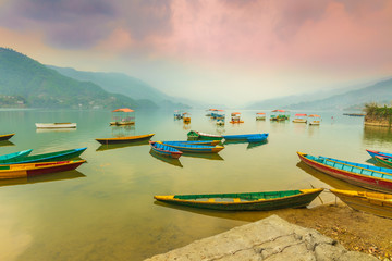 Fototapeta na wymiar Colorful boats parked in Phewa lake waiting for tourists and background on sunset