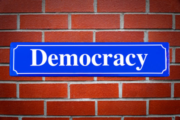 Democracy street sign on brick wall