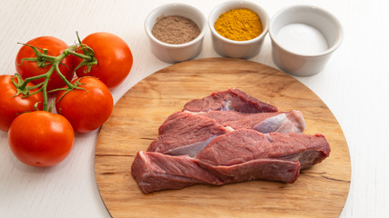 Fresh slice of beef close-up. Preparation for cooking red meat with spice and tomato.