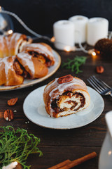 Piece of Swedish tea ring Christmas cake with cinnamon, pecans and raisins on a warm knitted sweater. The concept of cozy winter Holidays and homemade bakery.