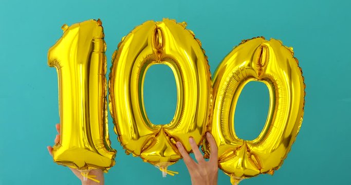 Gold foil number 100 one hundred celebration balloon on a blue background