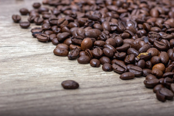 Roasted coffee beans, on a wooden surface.