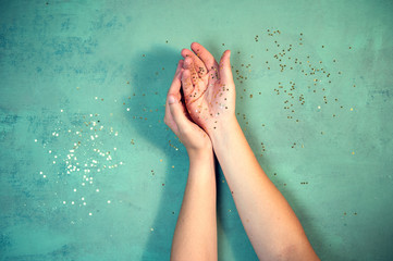 Top view woman's hands covered with golden stars confetti. Christmas celebration concept