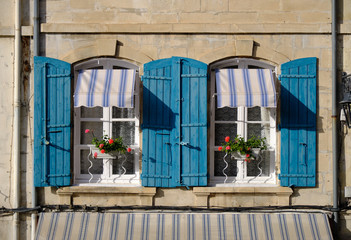 Typical house in Arles, Provence, with blue shutters and windowboxes with geraniums on a bright sunny afternoon