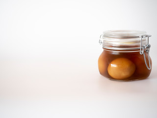 Brown, pickled, marinated eggs in glass jar on white background