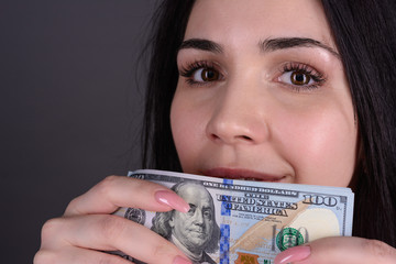 Close-up portrait of woman greedy for money smelling cash. holding bundle of dollars close to her face. dream of buying. venality concept.